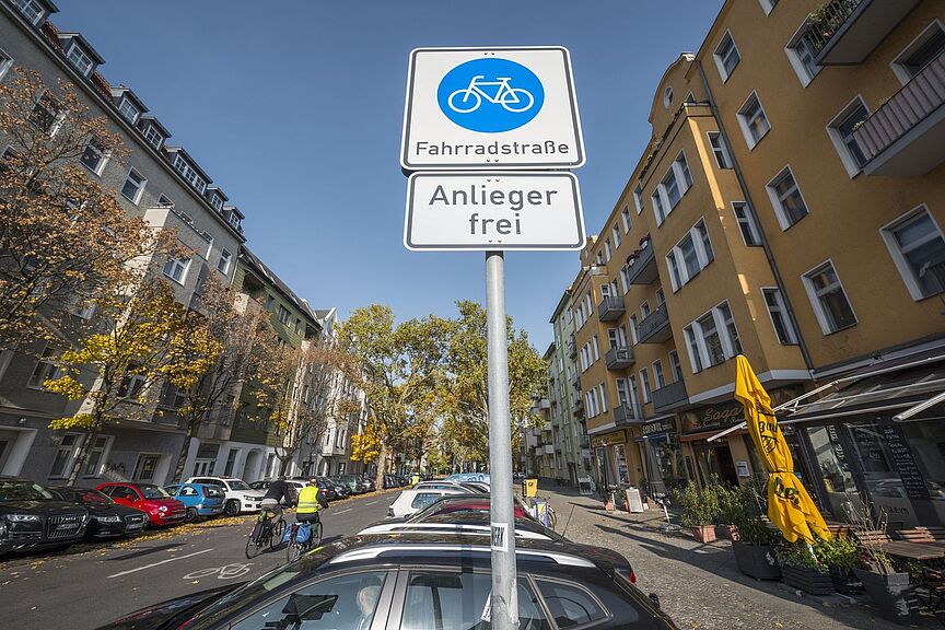 Fahrradfahren in der Stadt Schild "Fahrrradstraße" mit Zusatzzeichen "Radverkehr frei" von schräg unten aufgenommen. Straßenszene im Hintergrund.